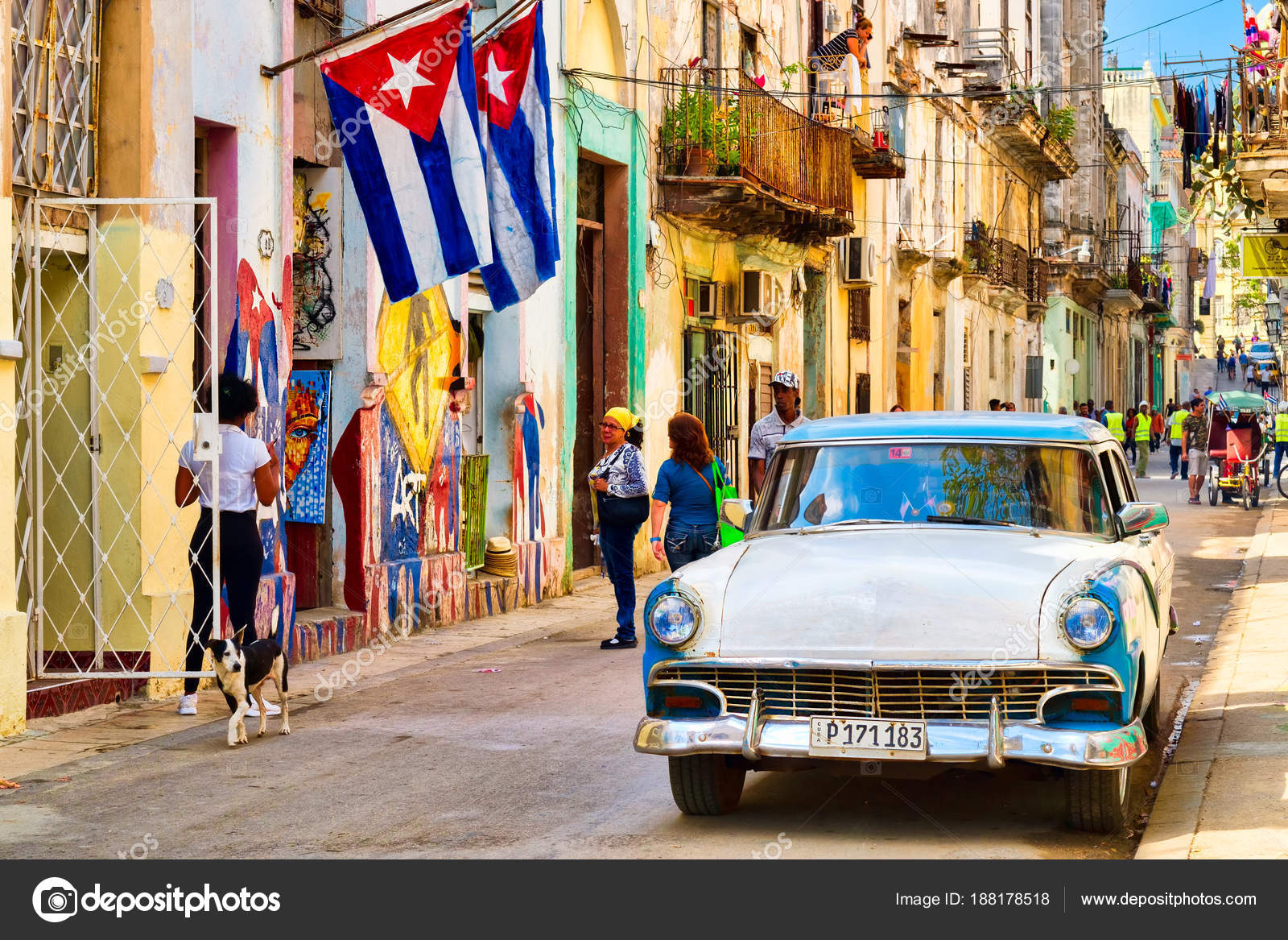 Cuban flags, classic car and colorful decaying buildings in Old Havana