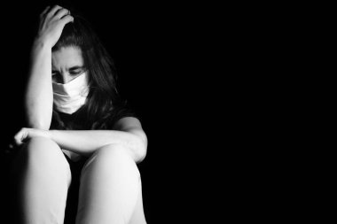 Hastalıktan korunmak için maske takan üzgün ve stresli bir kadın.