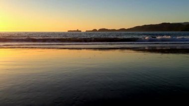 Gün batımında dalgalar yavaşça sahile doğru ilerliyor. 