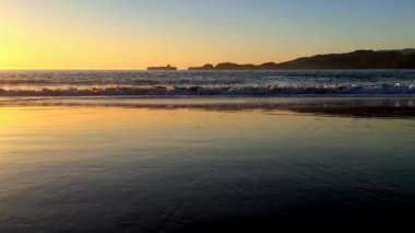 Gün batımında dalgalar yavaşça sahile doğru ilerliyor. 