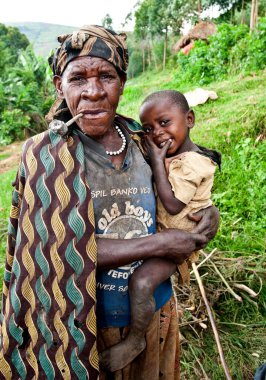 BUNYONYI Gölü, UGANDA - 21 Ekim 2012 'de Uganda' daki Bunyonyi Gölü 'nde kimliği belirsiz Batwa kadını ve çocuğu. Domuzlar ormanlarda yaşayan eski insanlardır. Ormanın Koruyucuları olarak bilinirlerdi.