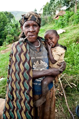 BUNYONYI Gölü, UGANDA - 21 Ekim 2012 'de Uganda' daki Bunyonyi Gölü 'nde kimliği belirsiz Batwa kadını ve çocuğu. Domuzlar ormanlarda yaşayan eski insanlardır. Ormanın Koruyucuları olarak bilinirlerdi.