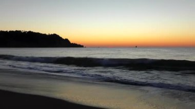 Su sıçratan deniz dalgaları üzerinde muhteşem renkli gün batımı