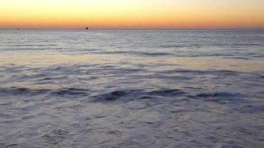 Su sıçratan deniz dalgaları üzerinde muhteşem renkli gün batımı