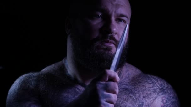Un gangster muscoloso barbuto tatuato e calvo con un coltello. 4K UHD — Video Stock
