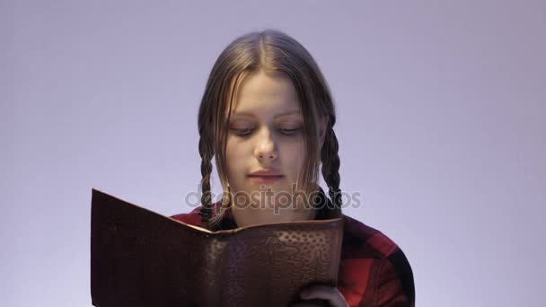 Menina adolescente com um sorriso astuto ler livro. 4K UHD — Vídeo de Stock