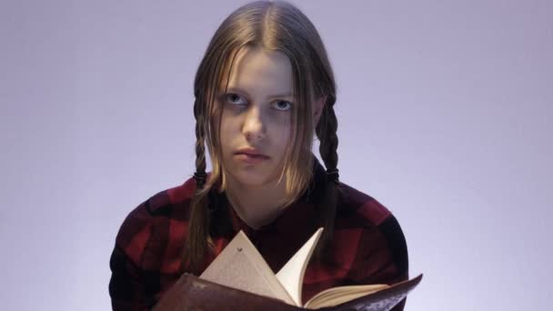 Geïrriteerde tiener meisje boek lezen en bekijken van camera. 4k Uhd — Stockvideo
