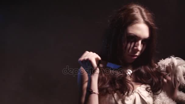 Страшная девушка-вампир с ножом и собачьей игрушкой выглядит злой и имеет зловещий взгляд. 4K UHD — стоковое видео