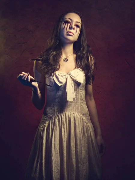 Chica vampiro con un cuchillo. La sangre sale de sus ojos —  Fotos de Stock