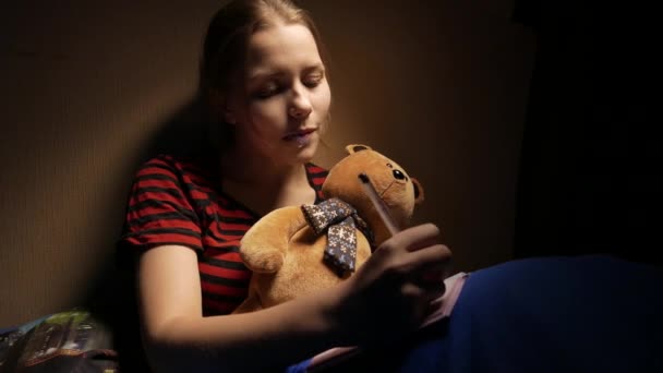 Adolescente escribiendo diario en casa en su mal con un oso de juguete y perrito. 4K UHD — Vídeo de stock