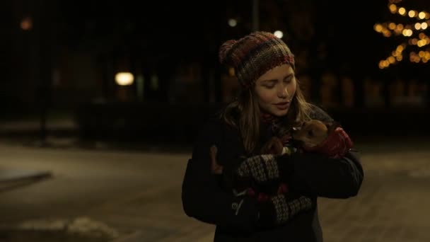 Tiener meisje met een klein hondje op een nacht koude straat. 4k Uhd — Stockvideo