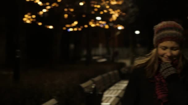 Jeune belle adolescente marchant la nuit en ville souriant. 4K UHD — Video