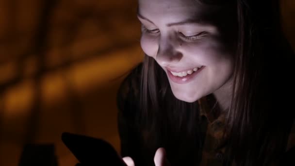 Девушка-подросток со смартфоном у окна, болтает и разговаривает. 4K UHD . — стоковое видео