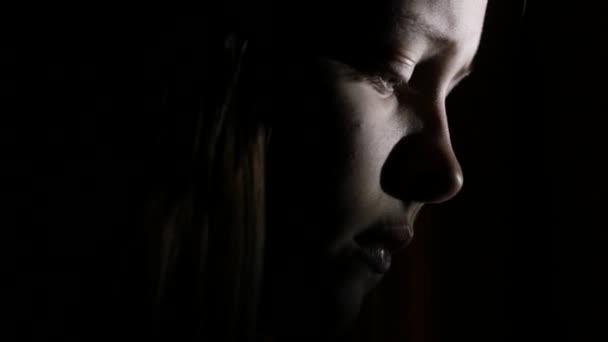 8Gros plan portrait d'une adolescente déprimée dans le noir. 4K UHD .