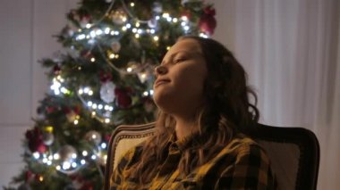 Genç kız gülümseyerek ve bir fincan çay içme. Noel ağacı ve tatil ruh hali. 4k Uhd.