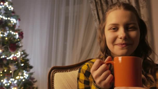 Genç kız gülümseyerek ve bir fincan çay içme. Noel ağacı ve tatil ruh hali. 4k Uhd. — Stok video
