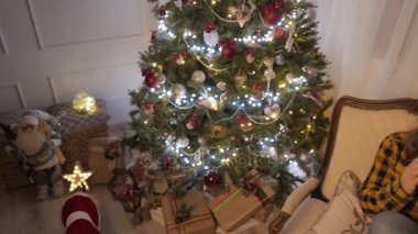 Genç kız gülümseyerek ve bir fincan çay içme. Noel ağacı ve tatil ruh hali. 4k Uhd.