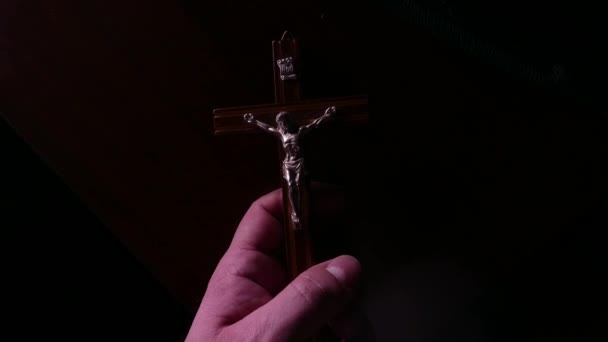 Main dans l'obscurité avec un crucifix en gros plan. 4K UHD 