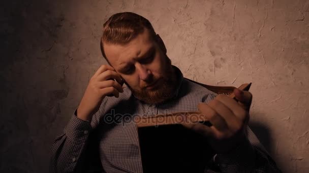 El hombre lee un libro en un cuarto oscuro y fuma pipa. 4K UHD — Vídeo de stock