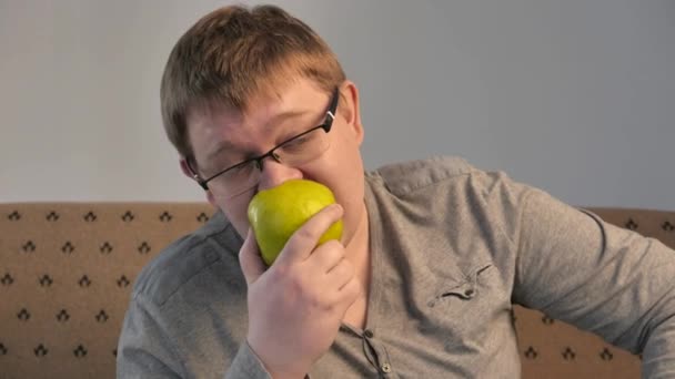 Hombre hambriento perezoso con sobrepeso comiendo manzana. 4K UHD — Vídeo de stock