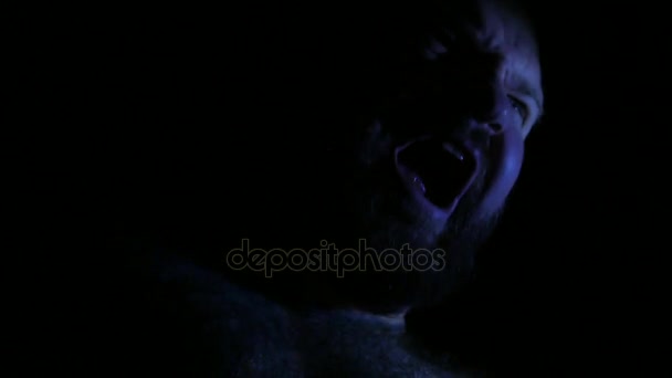 Portrait d'un homme jurant émotionnellement dans l'obscurité. L'homme agressif en colère est en conflit avec quelqu'un. Situation conflictuelle. 4K UHD 