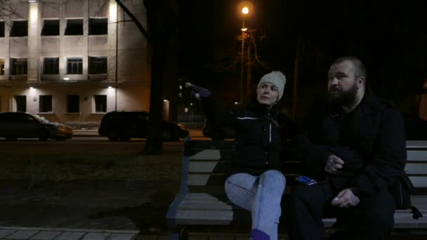 Paar zittend op het bankje bij nacht — Stockvideo
