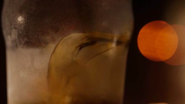 Cocktail de couleur foncée avec glace. Gros plan sur un fond flou . — Video