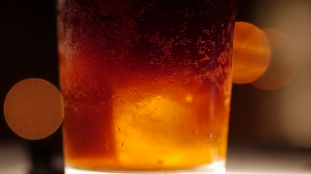 Donker gekleurde cocktail met ijs. Closeup geschoten op een onscherpe achtergrond. — Stockvideo