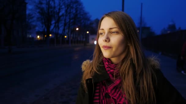 Retrato de una linda chica adolescente sonriente pensativa en una calle nocturna de la ciudad . — Vídeos de Stock