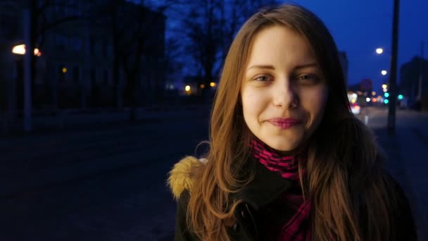 Retrato de una linda chica adolescente sonriente pensativa en una calle nocturna de la ciudad . — Vídeos de Stock