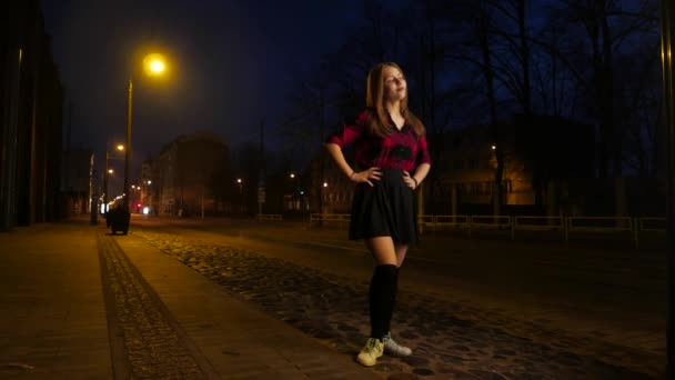 Schattig peinzende lachende tiener meisje op een nacht stad straat. — Stockvideo
