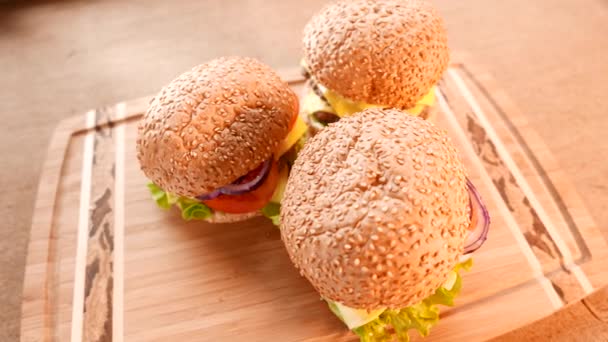 Drie verse smakelijke hamburgers met een salade en tomaat — Stockvideo