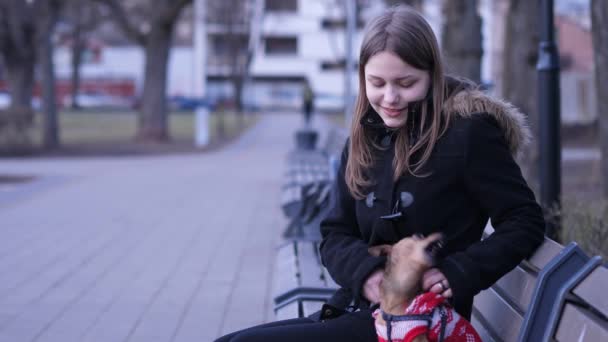 Menina adolescente e um pouco de terrier irritado jogando em um parque. 60 a 24fps — Vídeo de Stock