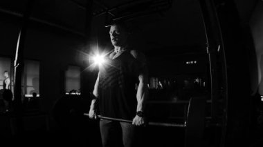 Bir spor salonunda eğitim genç vücut geliştiricisi. Dramatik siyah ve beyaz görüntüleri.