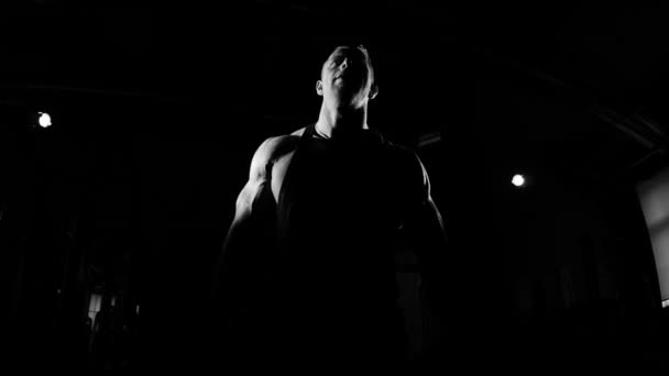 Junger Bodybuilder beim Training in einem Fitnessstudio. Dramatisches Schwarz-Weiß-Filmmaterial. — Stockvideo