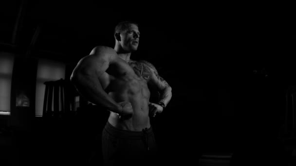 Jonge bodybuilder trainen in een sportschool. Dramatische zwart-wit beelden. — Stockvideo