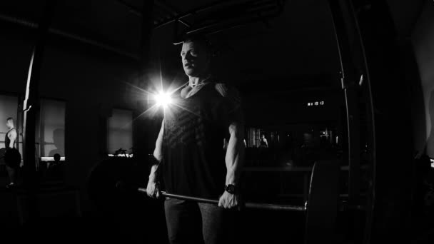 Jeune bodybuilder entraînement dans une salle de gym. Images dramatiques en noir et blanc . — Video