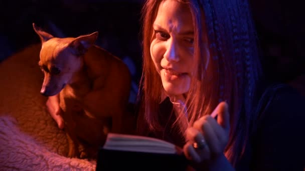 Menina adolescente lendo livro assustador à noite — Vídeo de Stock