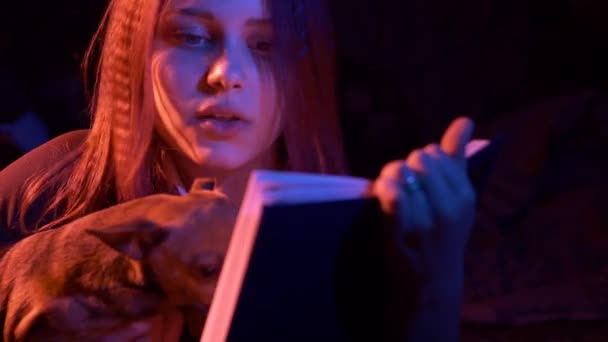 Adolescente chica leyendo aterrador libro en la noche — Vídeo de stock