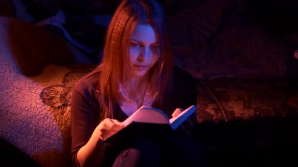 Дівчина-підліток читає страшну книгу вночі — стокове відео