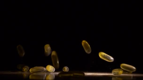 Pil capsule vallen en morsen op zwart oppervlak in slow motion — Stockvideo