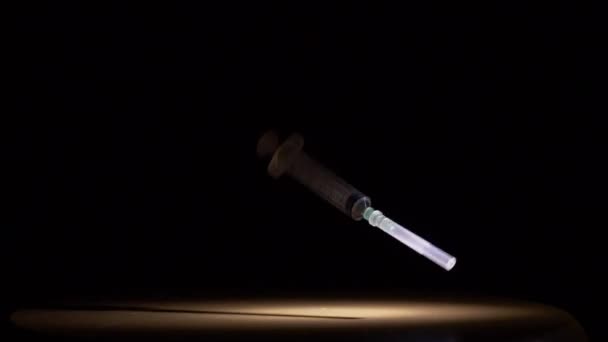 A medical syringe falls on a black background slow motion — Stock Video