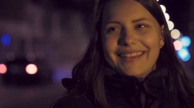 Bir şirin dalgın gülümseyen genç kız bir gece şehir sokak üzerinde portresi. 4 k Uhd slowmo