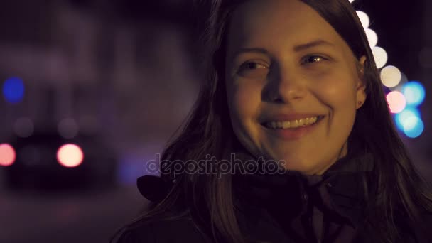 可爱沉思微笑的年轻女孩在夜晚的城市街道上的肖像。4 k 到 slowmo — 图库视频影像