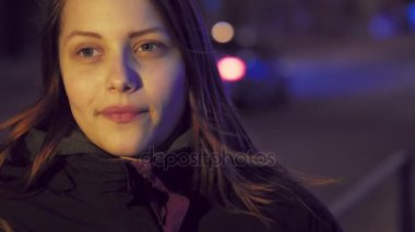 Bir şirin dalgın gülümseyen genç kız bir gece şehir sokak üzerinde portresi. 4 k Uhd slowmo