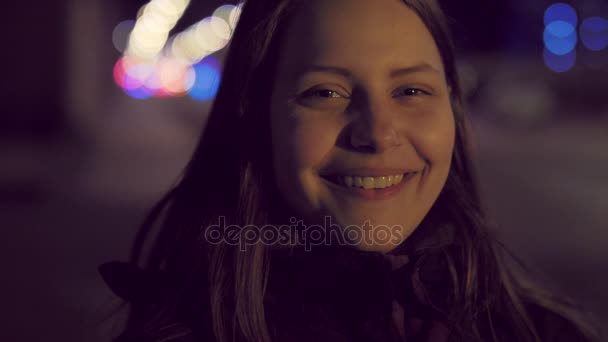 Retrato de una linda chica adolescente sonriente pensativa en una calle nocturna de la ciudad. lentitud UHD 4K — Vídeo de stock