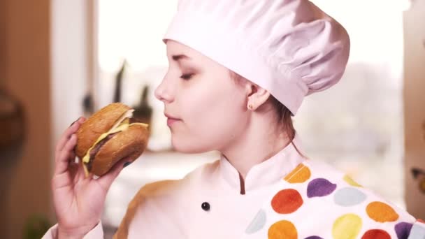 Belle jeune fille blonde cuisinière avec hamburger. 4K — Video