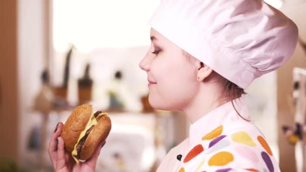 Hermosa chica rubia cocinera joven con hamburguesa. 4K — Vídeos de Stock