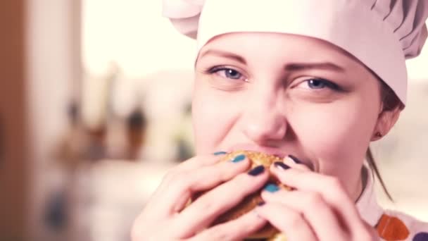 Mooie blonde jonge kok meisje met hamburger. 4k — Stockvideo