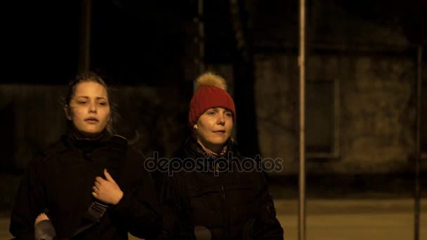 Moeder en dochter lopen op een nacht straat 4k slowmo — Stockvideo